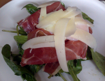 An arugula and warm asparagus salad topped with softly poached egg, Serrano ham, and manchego cheese.