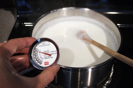 A meat thermometer measuring the temperature of a pot of milk
