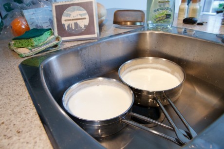 Two saucepans of milk cooling in a coldwater bath